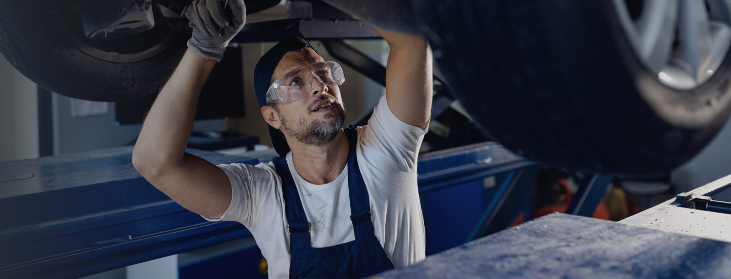 A man in an autoshop works under a car.